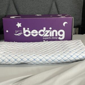 A box sitting on top of a bed next to a pillow.