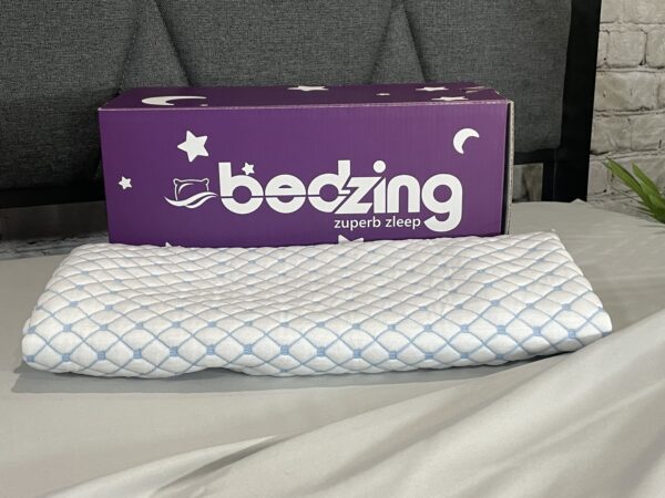 A box sitting on top of a bed next to a pillow.